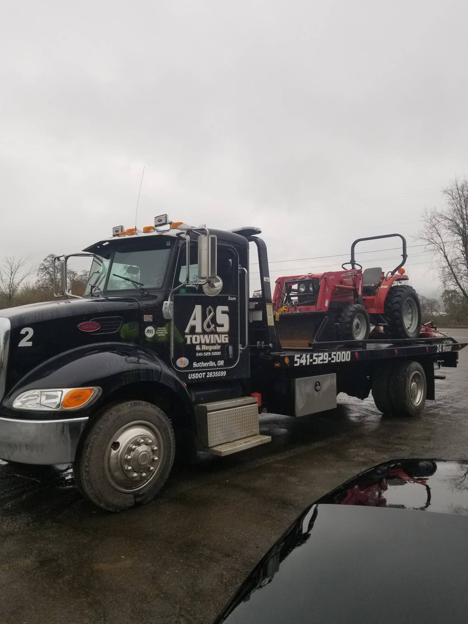 A&S flatbed hauling a red tractor