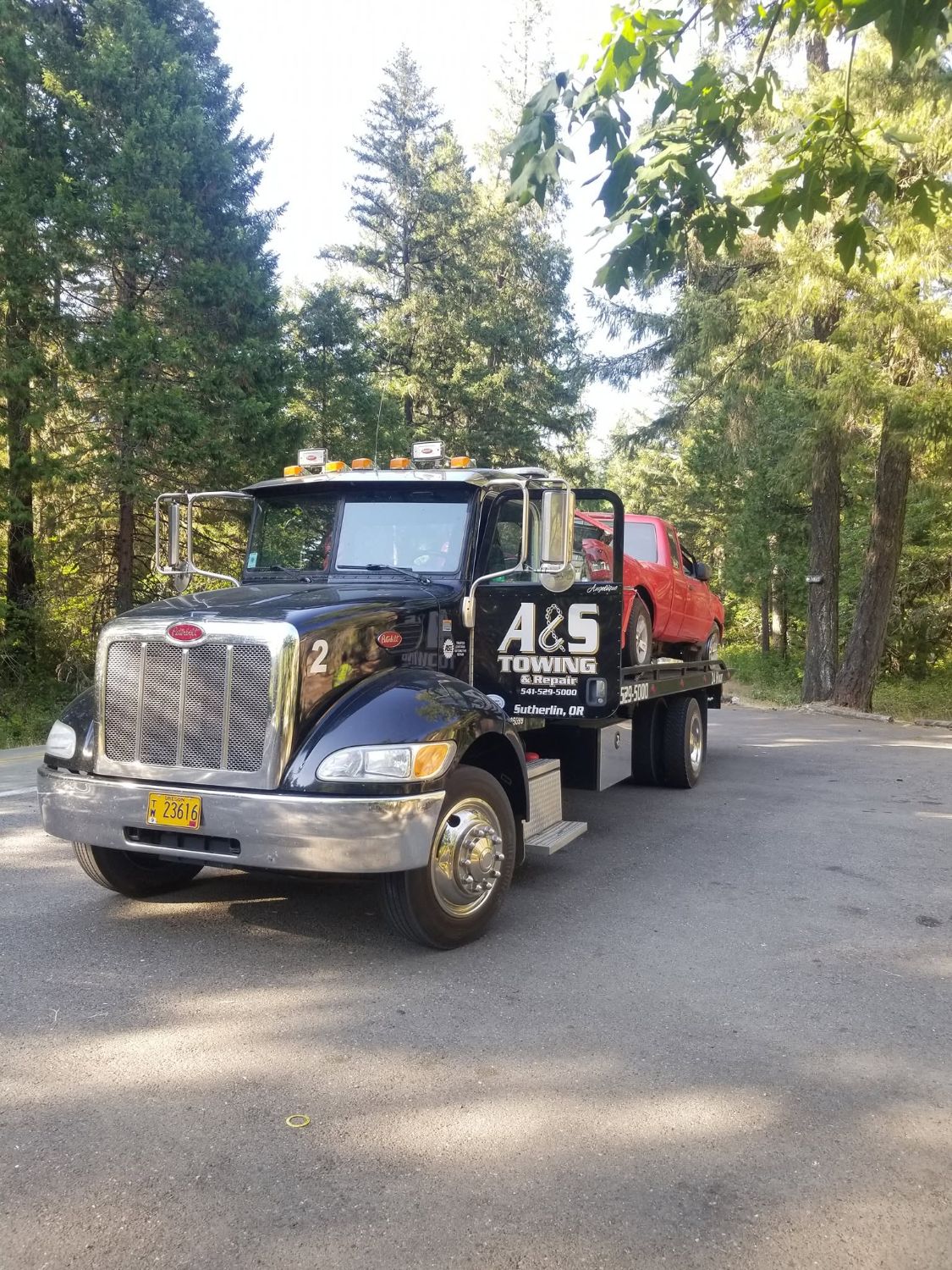 A&S Peterbilt flatbed with red truck in the forest